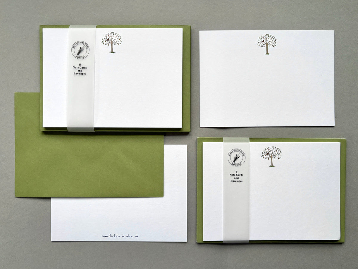 Christmas stationery sets arranged on a grey background, including packs of 6 and 10 Partridge Christmas note cards with matching olive green envelope. Also show is both front a reverse (with Blue Lobster Cards website address in small print) of a single partridge card  alongside a sample olive green envelope.