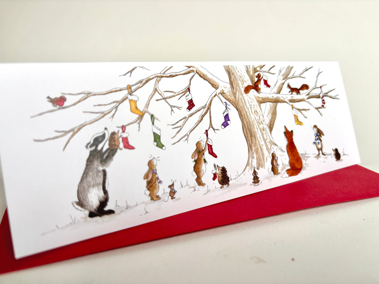 Long slim Animal Charity Christmas Card with crimson envelope featuring British animals hanging Christmas stockings on a snowy Christmas Eve