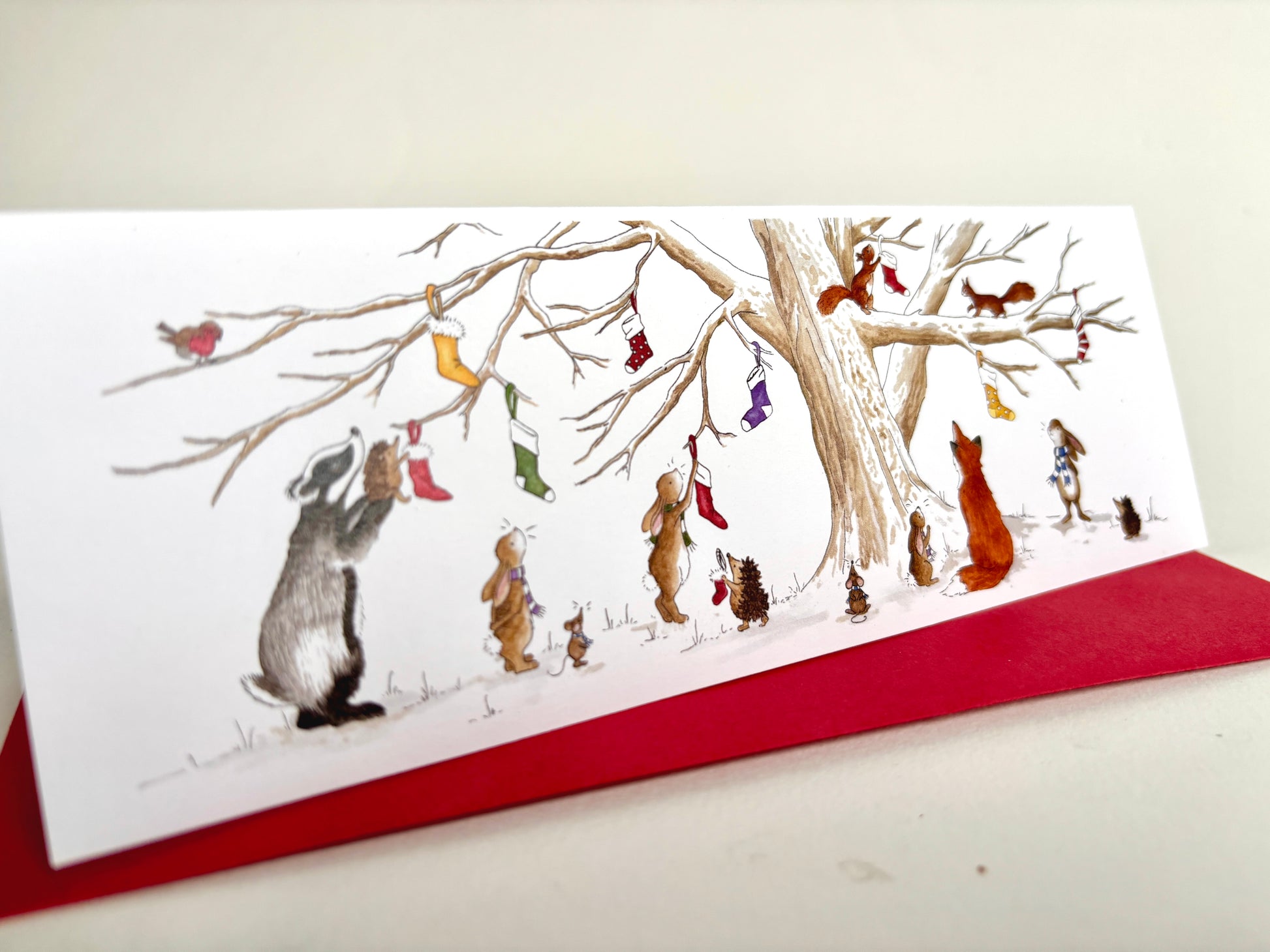 Long slim Animal Charity Christmas Card with crimson envelope featuring British animals hanging Christmas stockings on a snowy Christmas Eve