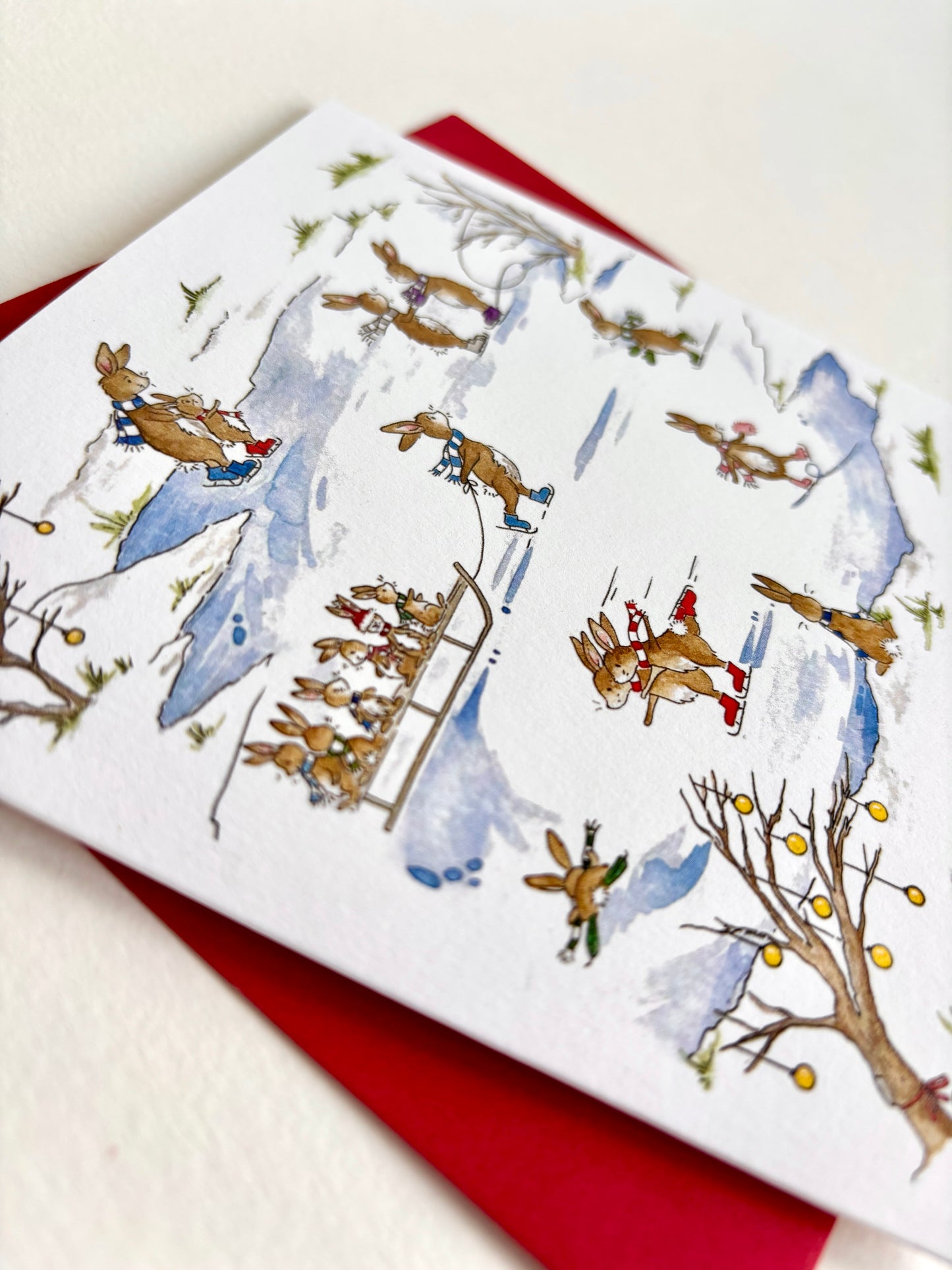 SHowing close-up of original watercolour illustration and fine quality softly textured matt cardstock - FSC certified, set against a festive red envelope.