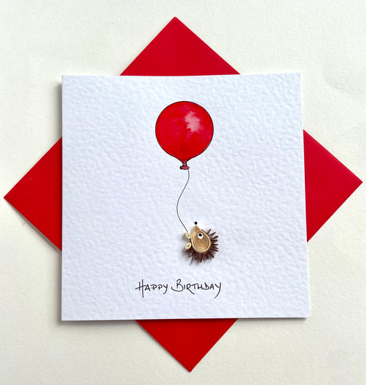 Greeting card with quilled 3D hedgehog floating up with a red balloon and 'Happy Birthday' text on a white background with a red envelope.