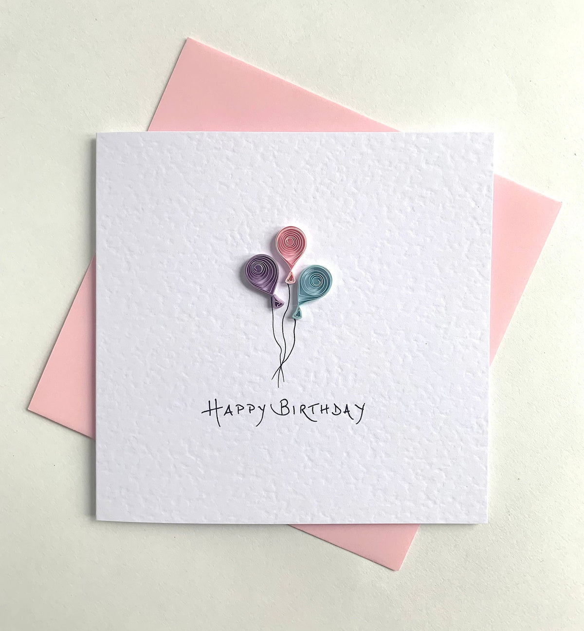 Handmade birthday card featuring 3 quilled balloons crafted from paper coils in shades of rose pink, turquoise and lilac. 