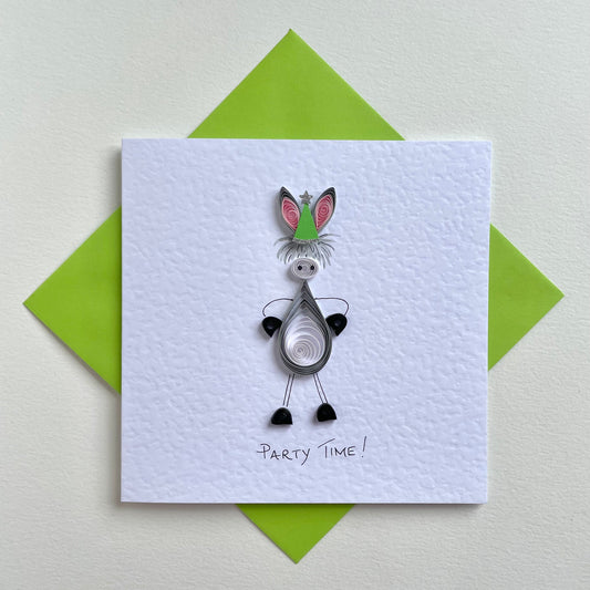 A handmade greeting card featuring a quilled paper donkey with green party hat, and the text 'Party Time' written at the bottom. The card is accompanied by a green envelope.