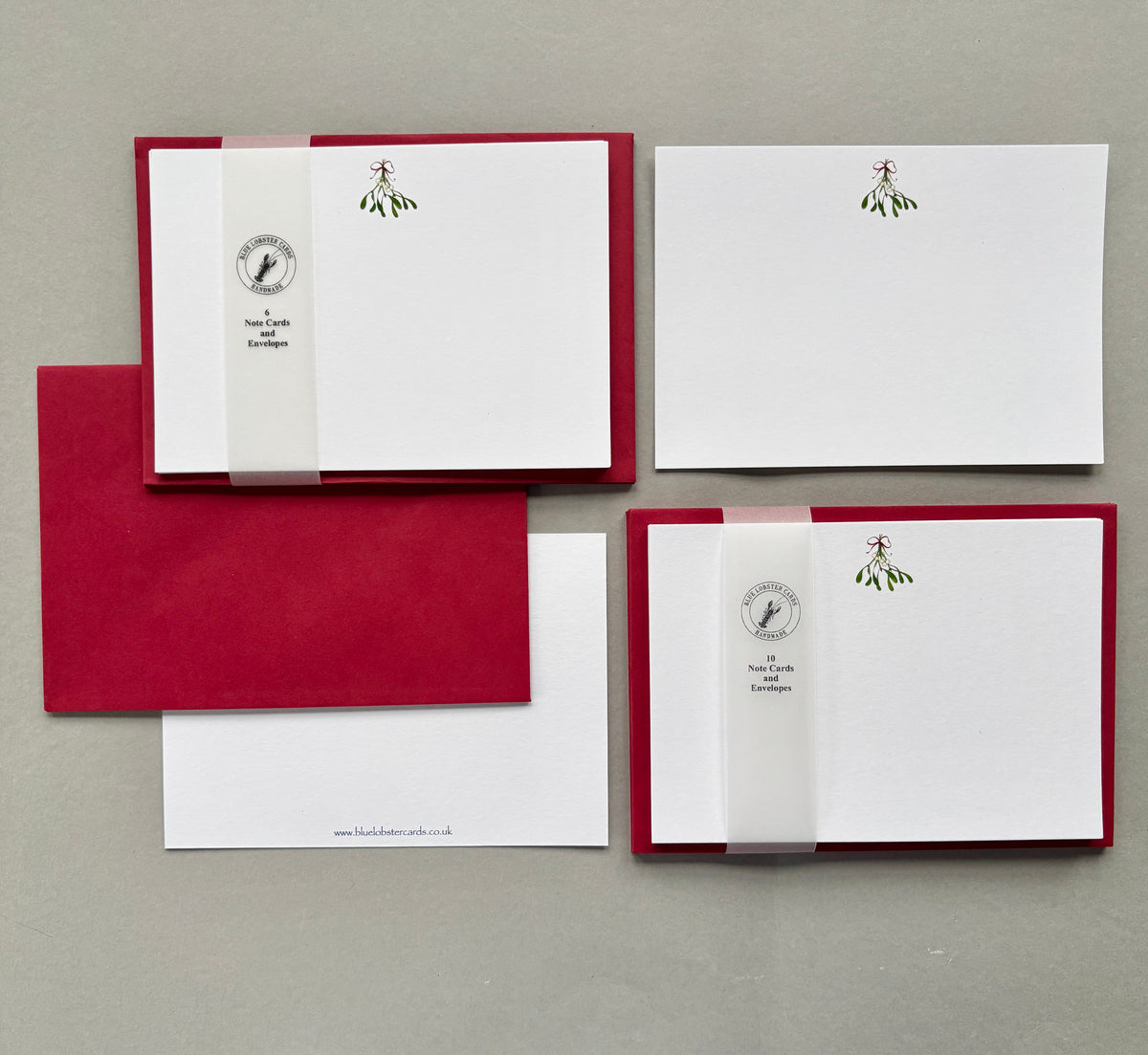 Two sets of Christmas stationery - packs of 6 or 10 on a neutral gray background. Printed using fine quality matt textured card, with with red envelopes with Blue Lobster Cards translucent belly band packaging. The reverse of the card is also shown with a sample matching envelope