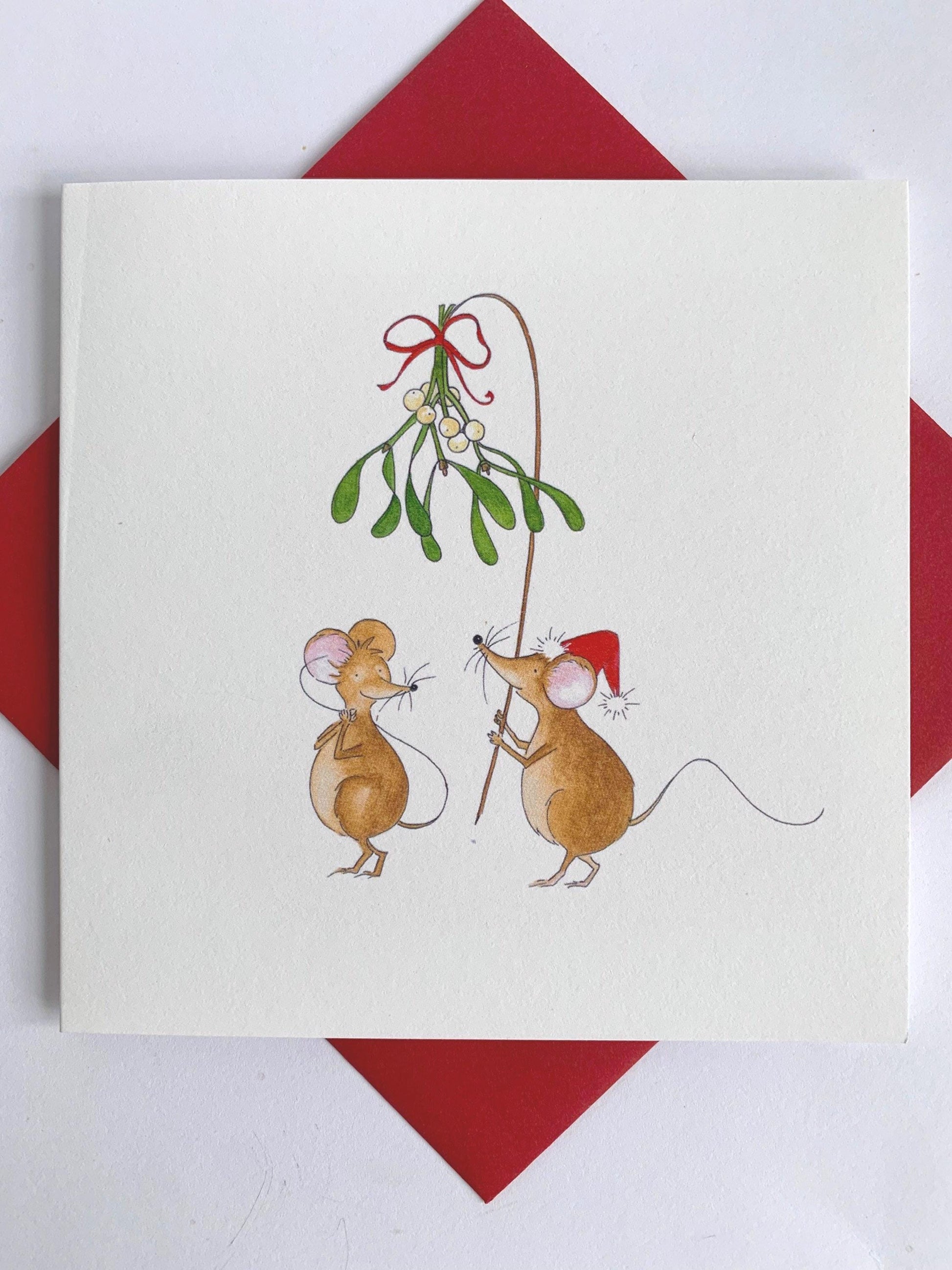 Square charity Christmas card set against coordinating red envelope shows two cute mice, one with a Christmas hat and holding aloft a branch of mistloe tied with red ribbon, hoping for a Christmas kiss. Designed and printed in the UK from original watercolour artwork