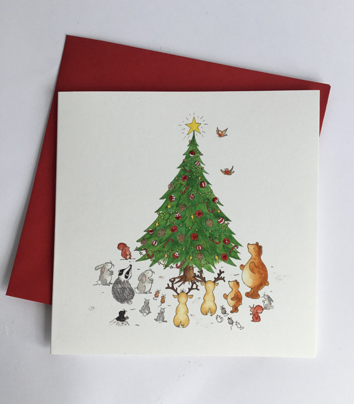 Square 135mm card of various animals around a beuatifully decroated Christmas tree, with coordinating christmas red envelope 