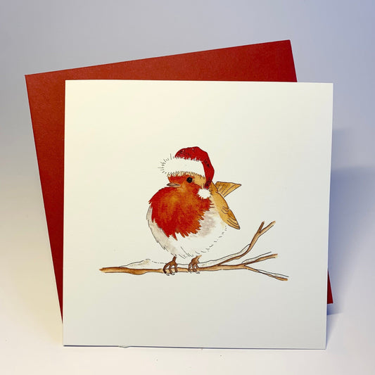 A traditional Christmas card featuring a hand-painted robin with a Christmas hat perched on a snowy branch, with red envelope