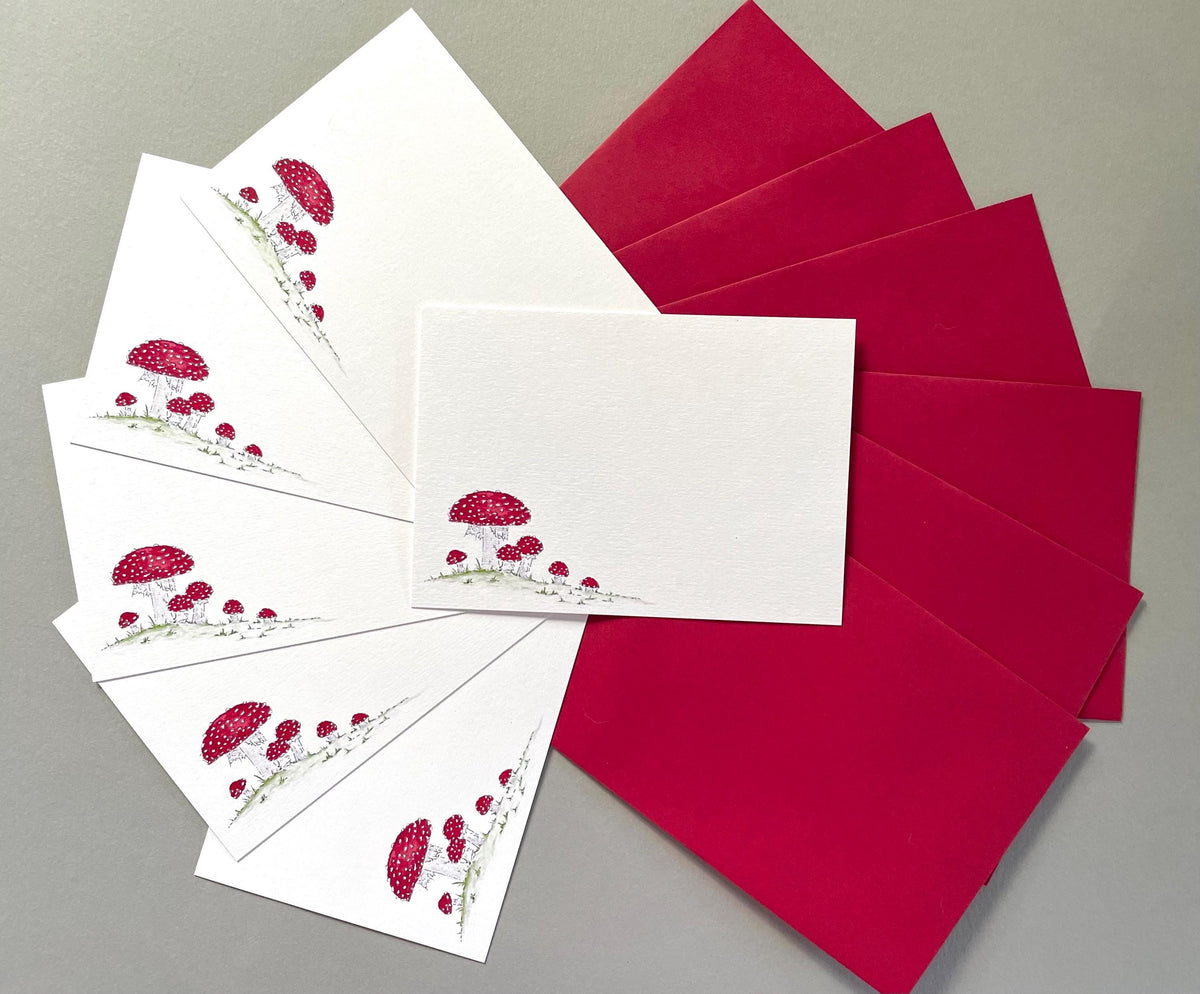 Packs of 6 or 10 notecards available featuring cluster of red and white spotted fungi with matching red envelopes