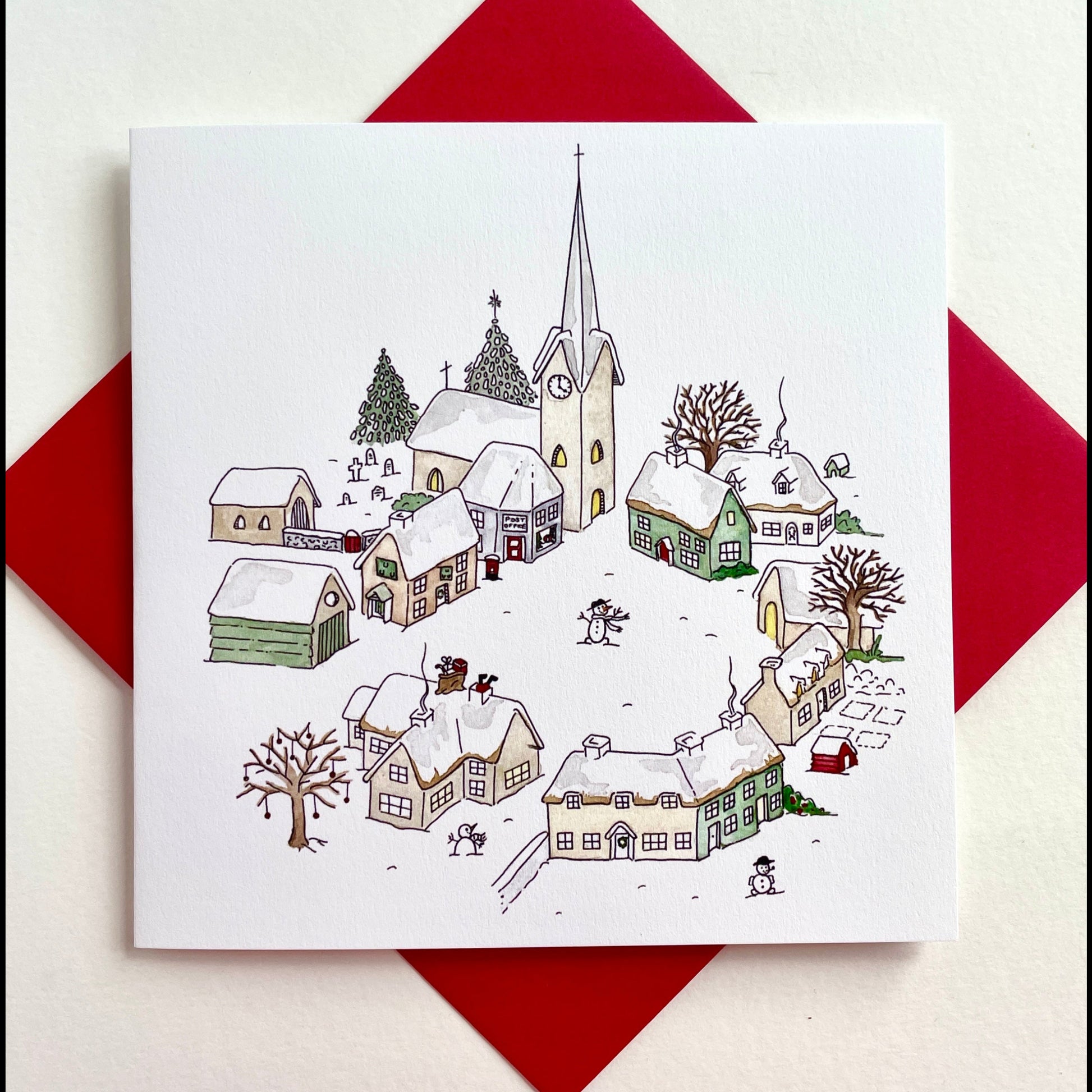 Original watercolour design of traditional snowy village at Christmas with church, cosy cottages, traditonal English pub with snowman and Father Christmas