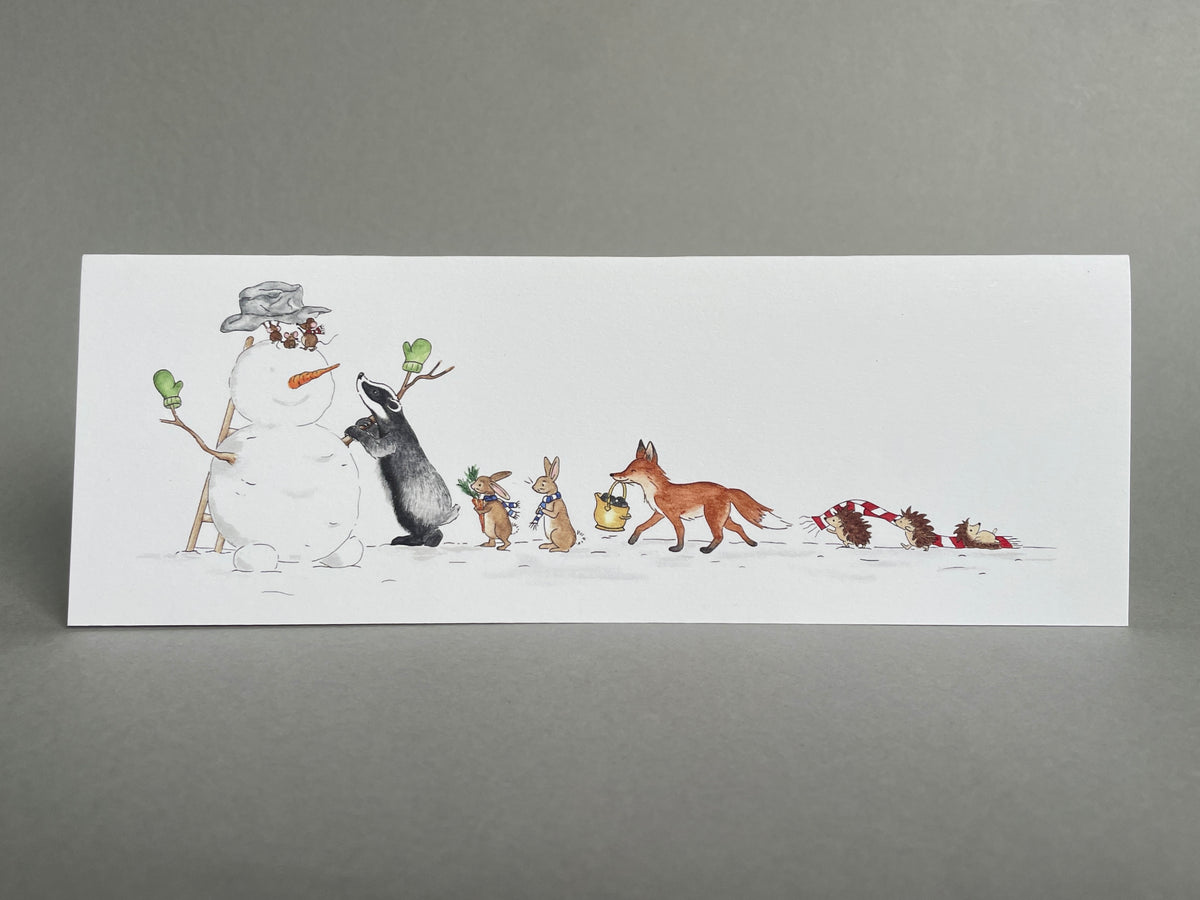 Front view of the woodland animals snowman Christmas card standing alone against a grey background.