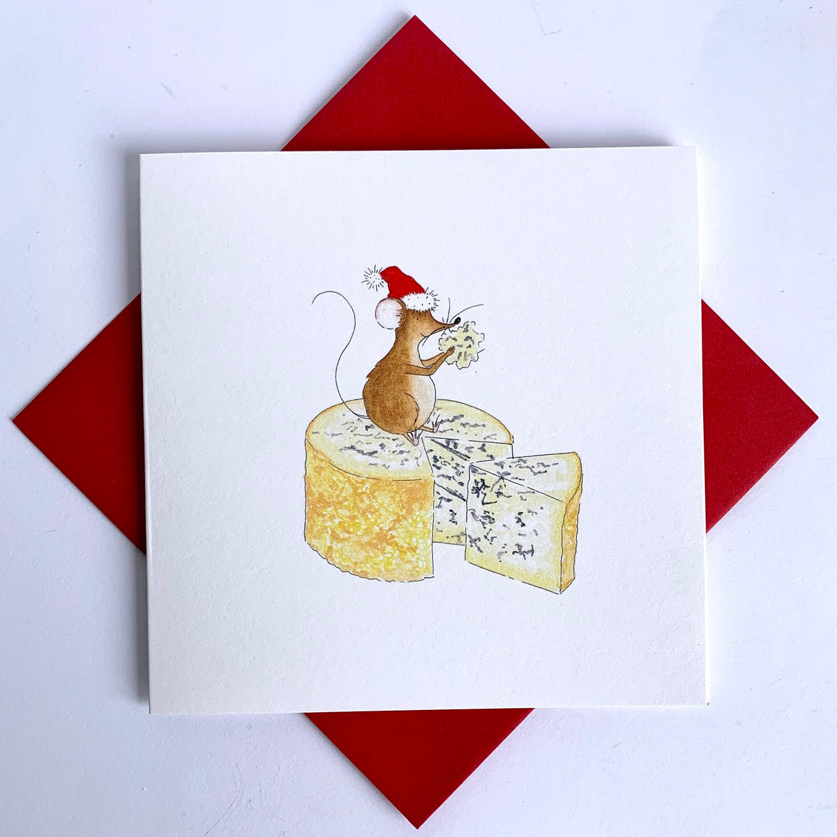 Delightful Animal Charity Christmas card featuring my own watercolour  illustration of a cute Christmas mouse sitting on top of a piece of Stilton cheese. Coordinating red envelopes supplied