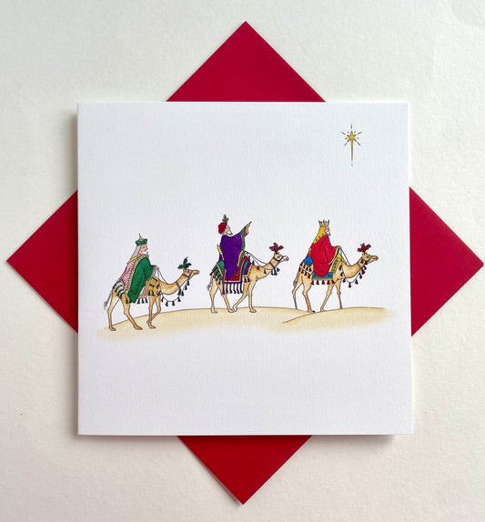 Square Christmas card with watercolour illustration of three wise men on camels with coordinating red envelope beneath