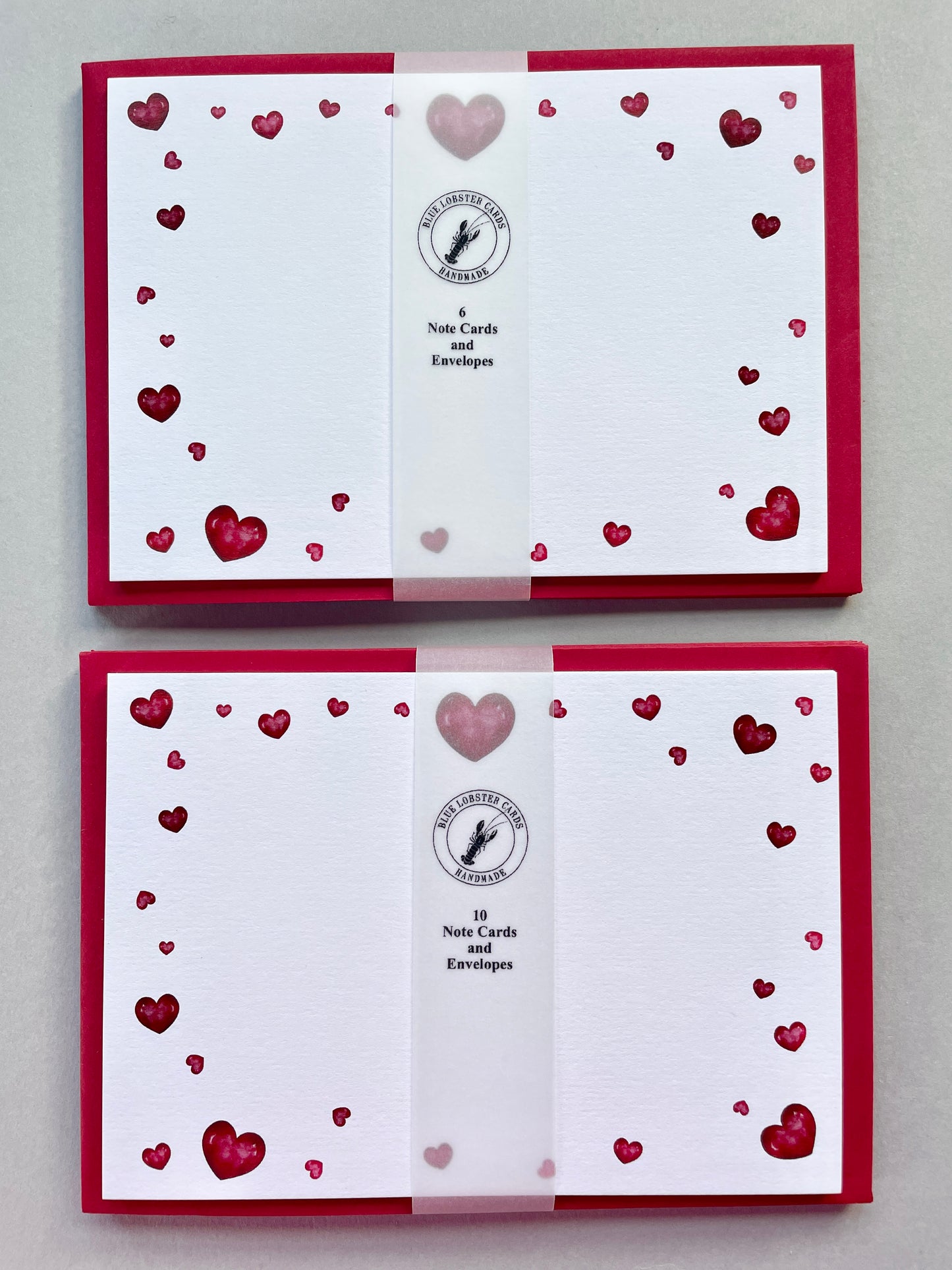 Sets of note cards with envelopes (6 or 10 per pack) with red heart designs on a white background